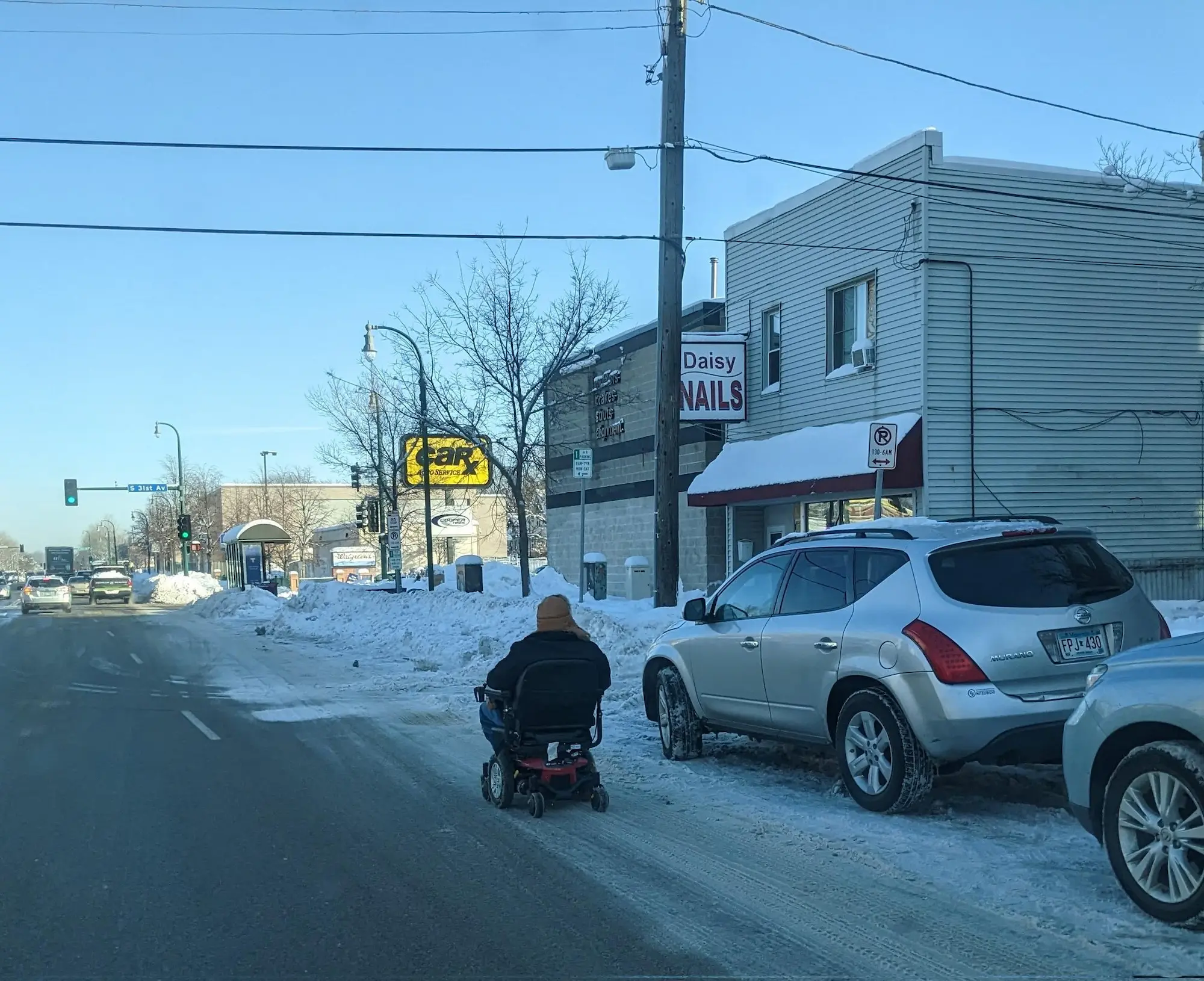 a person using wheelchair on busy street because sidewalks haven't been shoveled