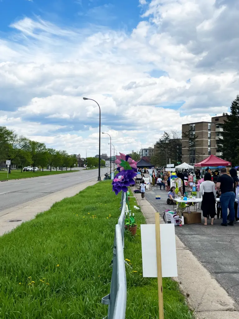 A photo of the Imagine 6th Avenue North event in 2022. On the left side of the image is Olson Memorial Highway, which is empty pavement. On the right side, on the frontage road, people enjoy the Imagine 6th Avenue north event.