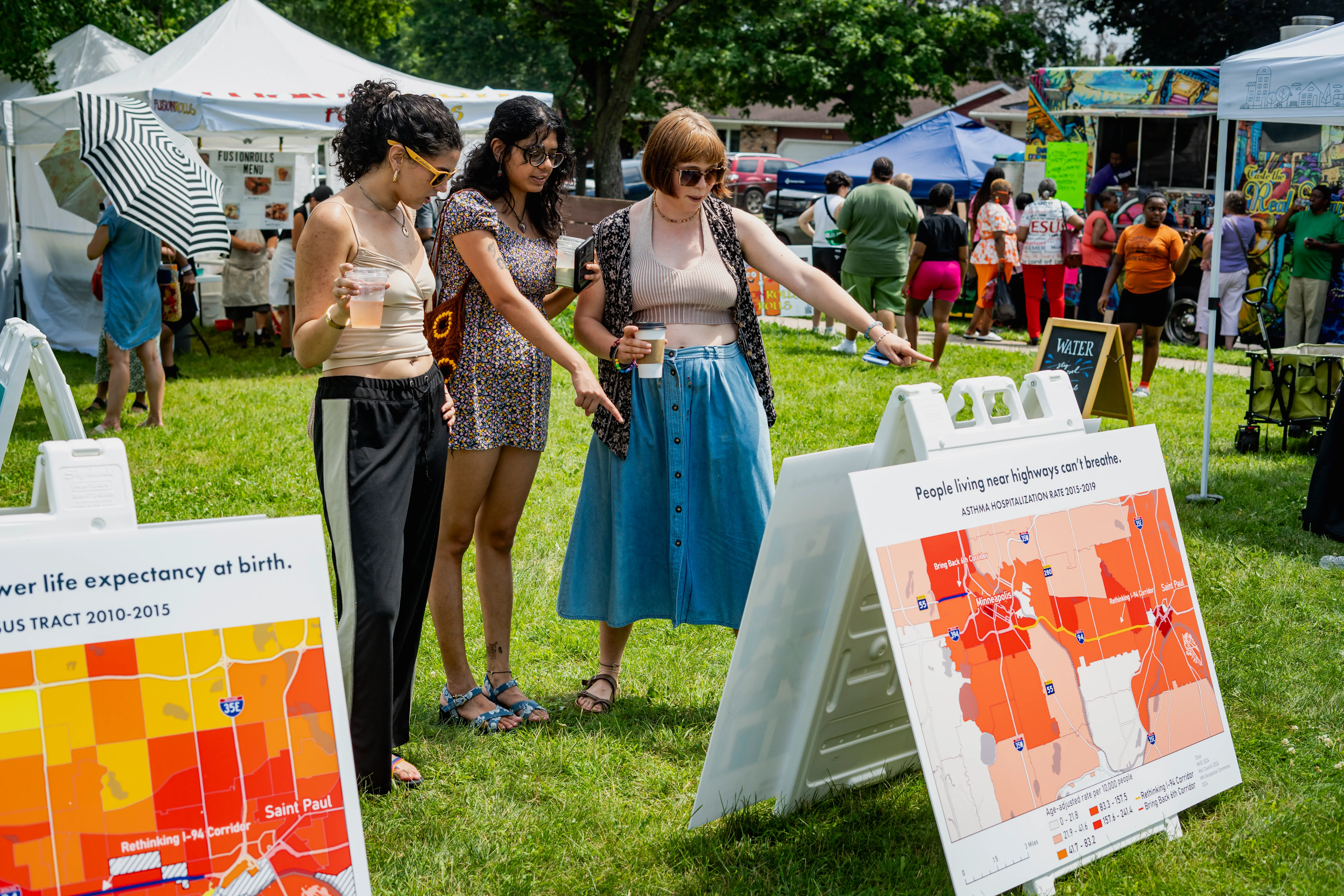 three people pointing at some of the resources available on highway harms at Imagine Frogtown & Rondo