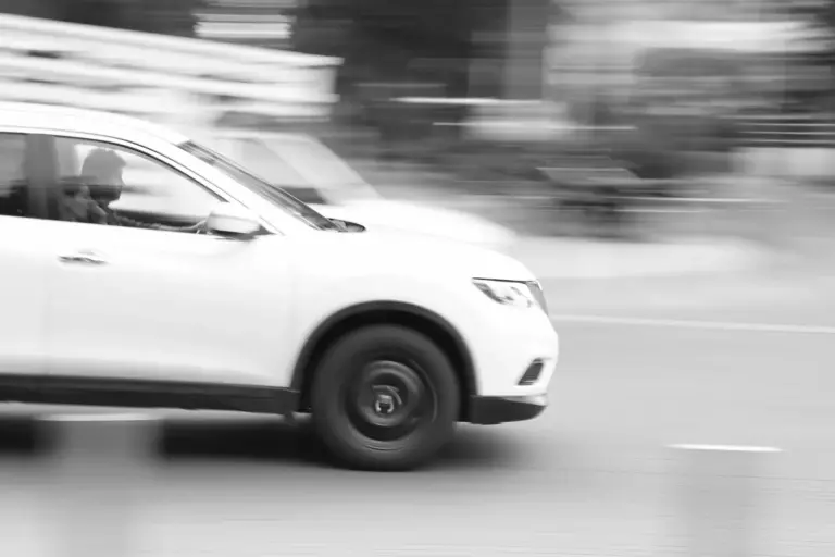 black and white image of car speeding, image blurry from speed