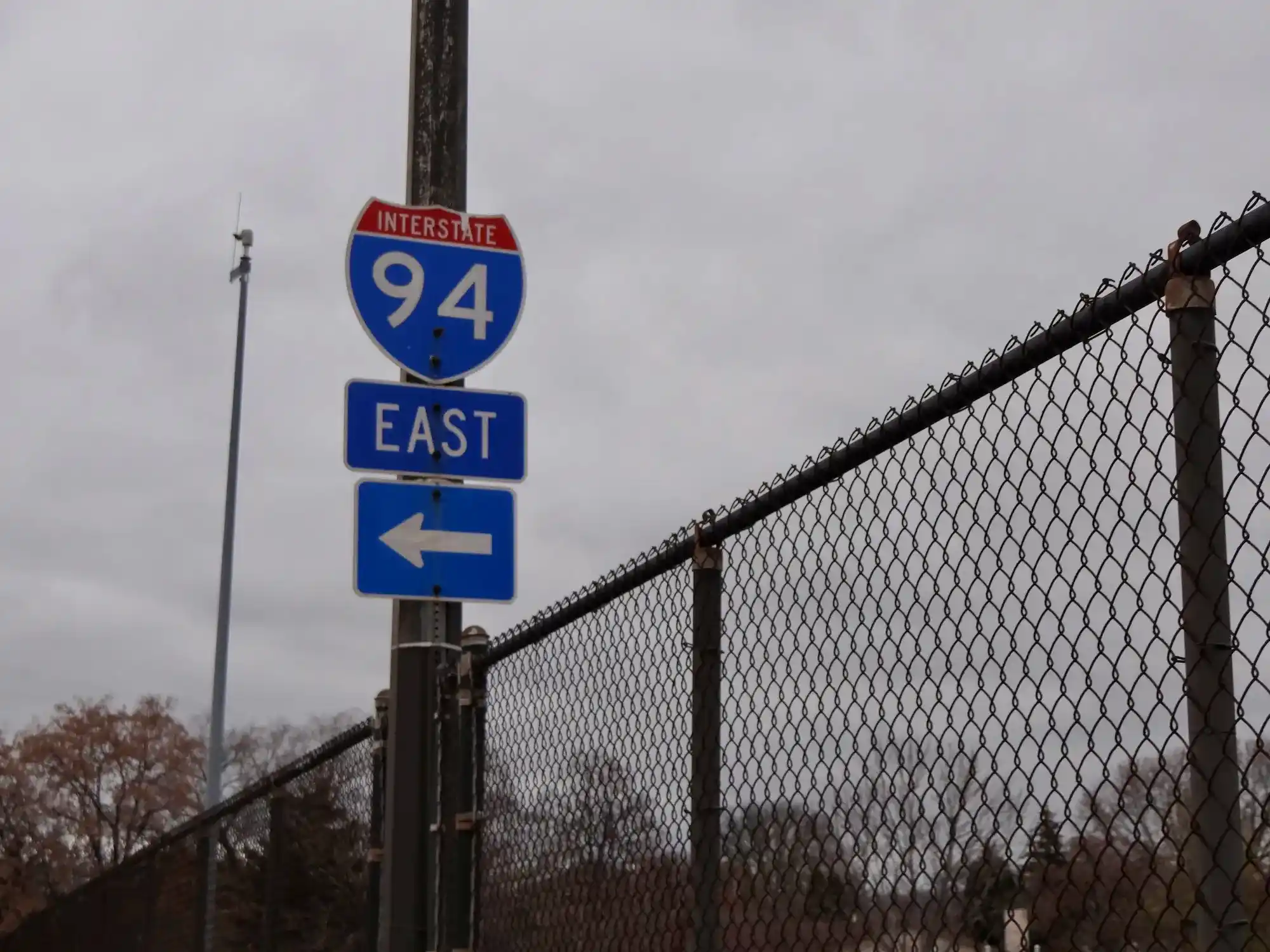 image of 94 east sign on with chain link fence over highway